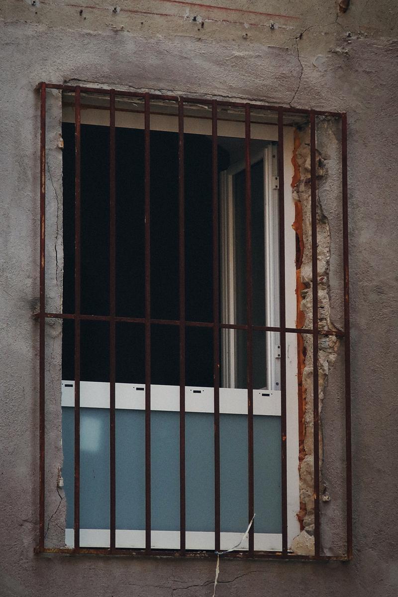 Fenêtre à barreaux sur une façade décrépie