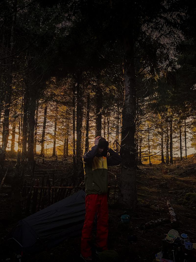 Randonneur dans une forêt sombre traversée de lumière dorée