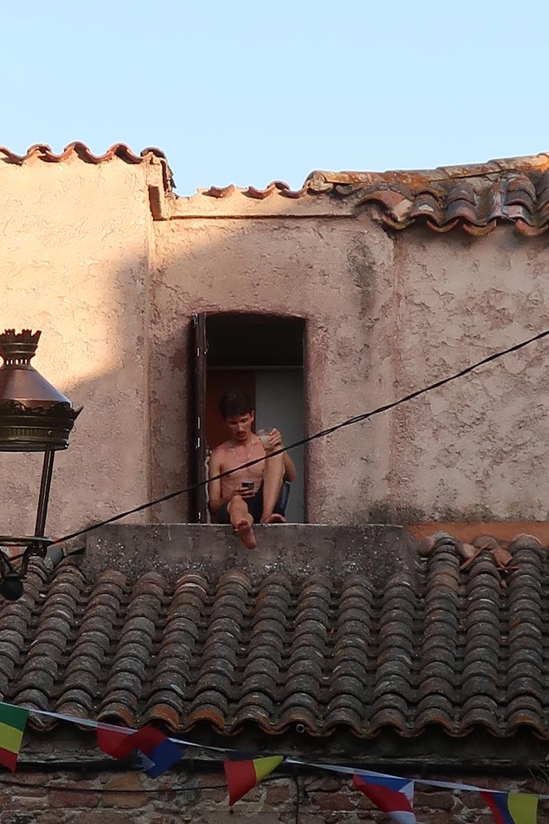 Homme assis à une fenêtre au-dessus des toits